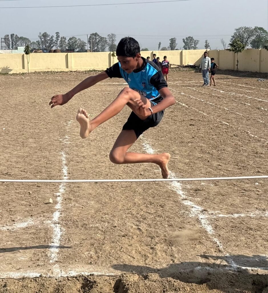 A student competing in the long jump during school sports.